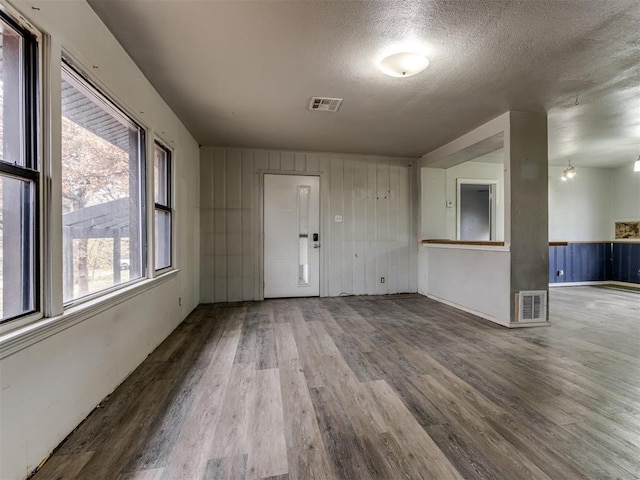 empty room with wood walls, wood-type flooring, and a textured ceiling