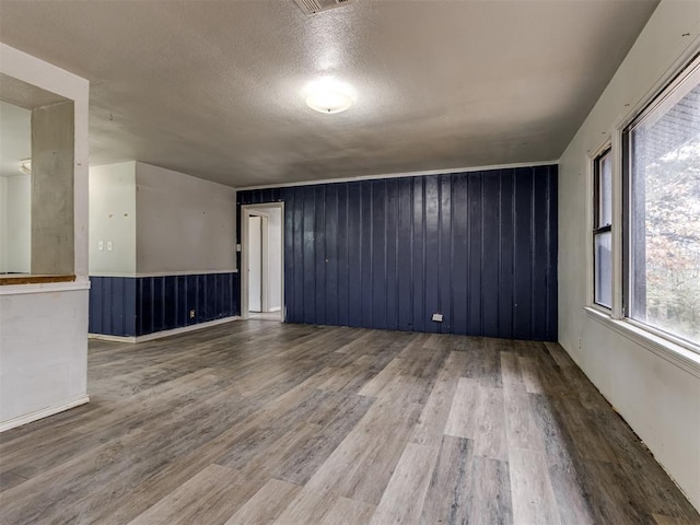 empty room featuring hardwood / wood-style floors, a textured ceiling, and wooden walls