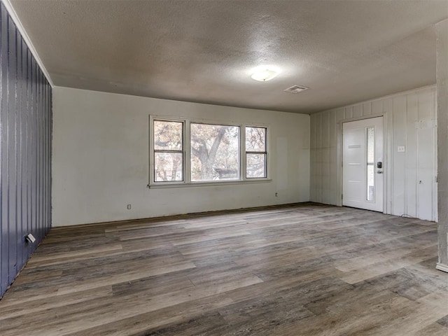 unfurnished room with a textured ceiling, hardwood / wood-style flooring, and wood walls