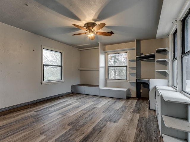 unfurnished office with ceiling fan, a healthy amount of sunlight, and wood-type flooring