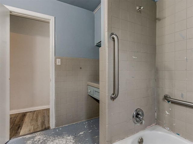 bathroom with hardwood / wood-style floors, tile walls, and tiled shower / bath