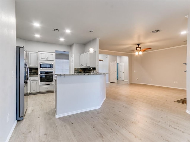 kitchen with white cabinets, hanging light fixtures, decorative backsplash, light wood-type flooring, and appliances with stainless steel finishes