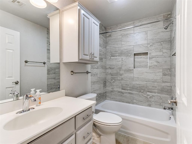 full bathroom with hardwood / wood-style floors, vanity, tiled shower / bath combo, and toilet