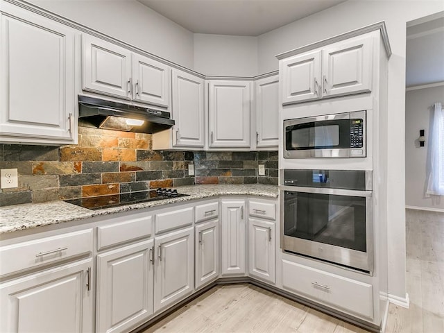 kitchen with light stone countertops, appliances with stainless steel finishes, tasteful backsplash, light hardwood / wood-style floors, and white cabinetry