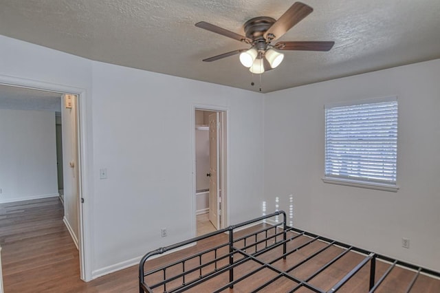 bedroom featuring wood-type flooring, a textured ceiling, ensuite bathroom, and ceiling fan