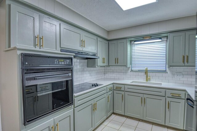 kitchen featuring gray cabinetry, sink, tasteful backsplash, light tile patterned floors, and black appliances