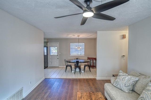 dining area with ceiling fan, wood-type flooring, and a textured ceiling