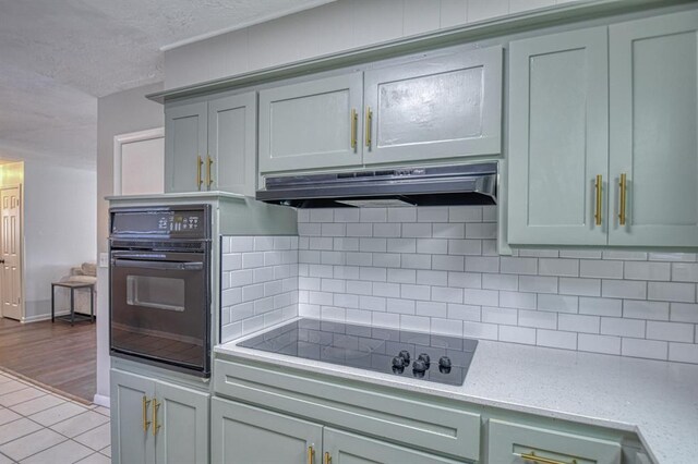 kitchen with light stone countertops, decorative backsplash, light hardwood / wood-style flooring, and black appliances