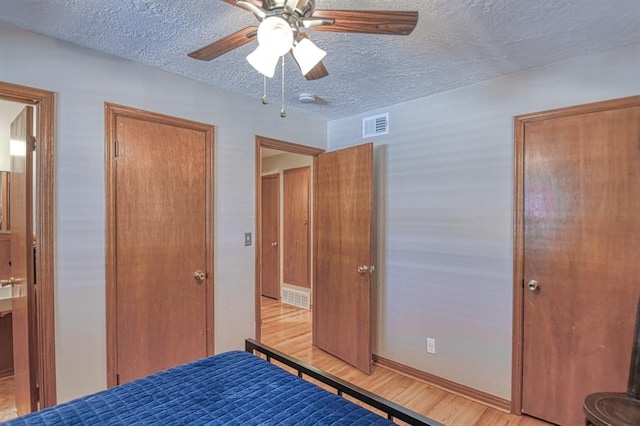 unfurnished bedroom with ceiling fan, a textured ceiling, and light wood-type flooring