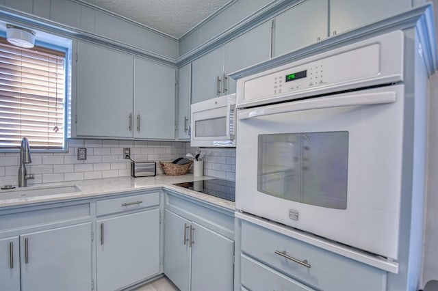 kitchen featuring a textured ceiling, backsplash, sink, and white appliances