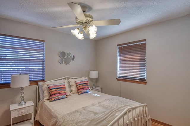 bedroom with hardwood / wood-style floors, a textured ceiling, and ceiling fan