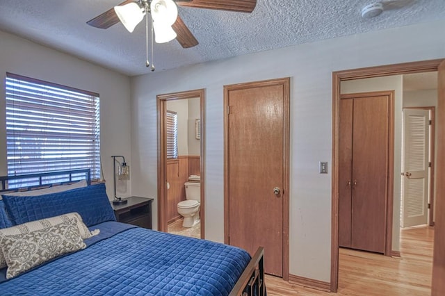 bedroom featuring a textured ceiling, light wood-type flooring, ensuite bathroom, and ceiling fan