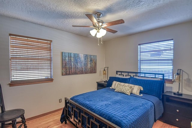 bedroom with hardwood / wood-style flooring, ceiling fan, a textured ceiling, and multiple windows