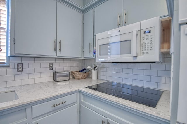 kitchen with light stone countertops, black electric cooktop, and tasteful backsplash