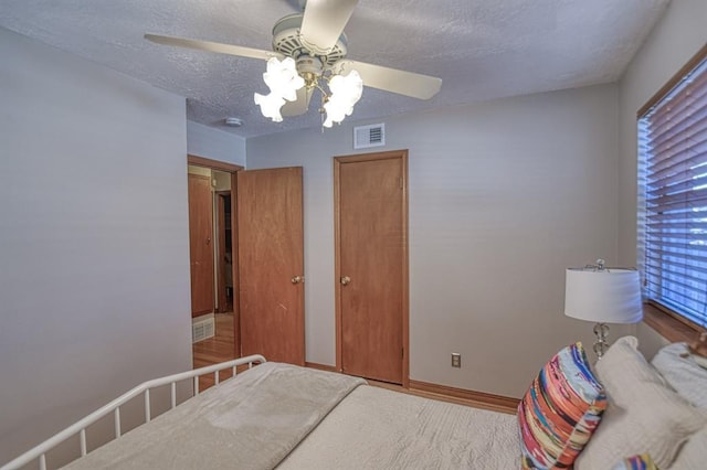 unfurnished bedroom with a textured ceiling, hardwood / wood-style flooring, and ceiling fan