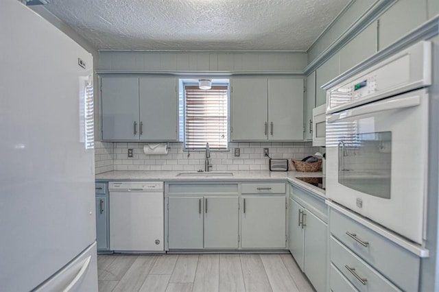 kitchen with tasteful backsplash, sink, a textured ceiling, and white appliances