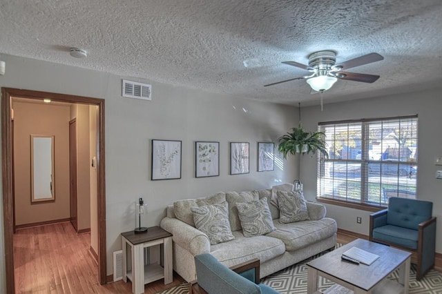 living room with ceiling fan, light hardwood / wood-style floors, and a textured ceiling