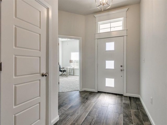 foyer entrance featuring dark wood-type flooring and an inviting chandelier