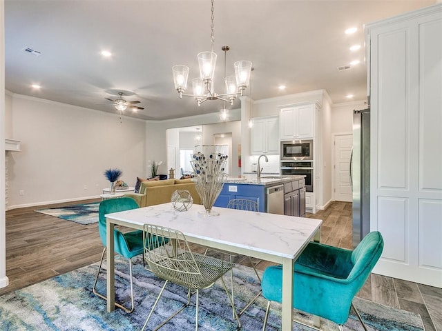 dining space featuring dark hardwood / wood-style floors, sink, ornamental molding, and ceiling fan with notable chandelier