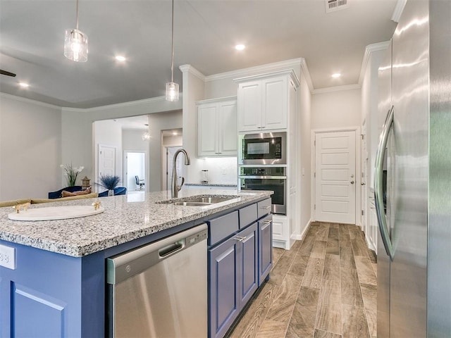 kitchen with a kitchen island with sink, sink, appliances with stainless steel finishes, decorative light fixtures, and white cabinetry