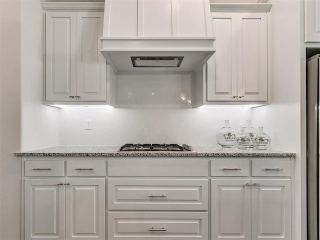 kitchen with white cabinets, light stone counters, custom range hood, and stainless steel appliances