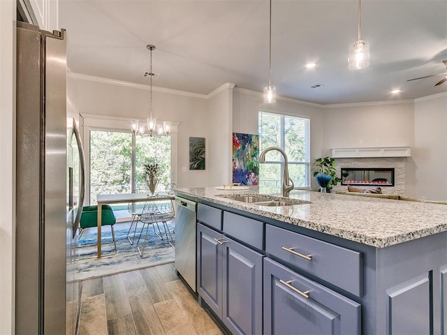 kitchen featuring crown molding, sink, an island with sink, appliances with stainless steel finishes, and light hardwood / wood-style floors