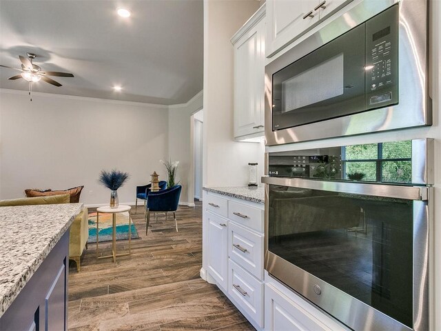 kitchen featuring dark hardwood / wood-style flooring, white cabinets, stainless steel appliances, and ornamental molding