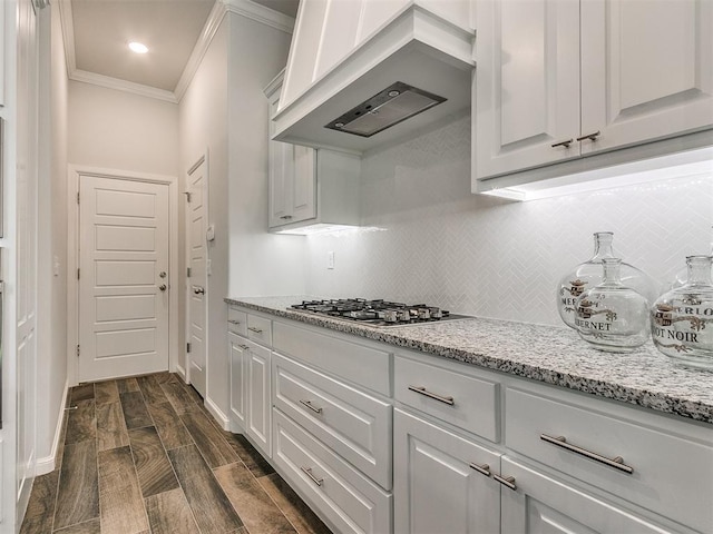 kitchen with dark hardwood / wood-style floors, light stone countertops, custom range hood, ornamental molding, and white cabinetry