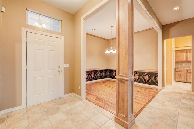 foyer entrance with an inviting chandelier, light hardwood / wood-style flooring, and crown molding