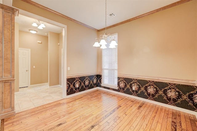 empty room featuring crown molding, light hardwood / wood-style flooring, and a chandelier