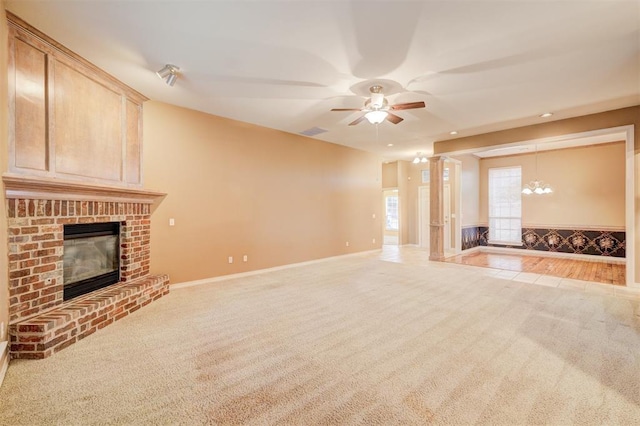 unfurnished living room featuring a fireplace, light colored carpet, and ceiling fan with notable chandelier