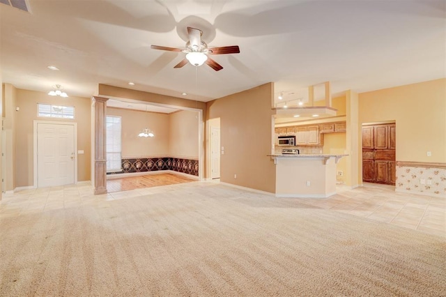 unfurnished living room featuring ornate columns, ceiling fan, and light tile patterned floors