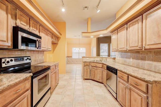 kitchen with appliances with stainless steel finishes, backsplash, track lighting, sink, and light tile patterned floors