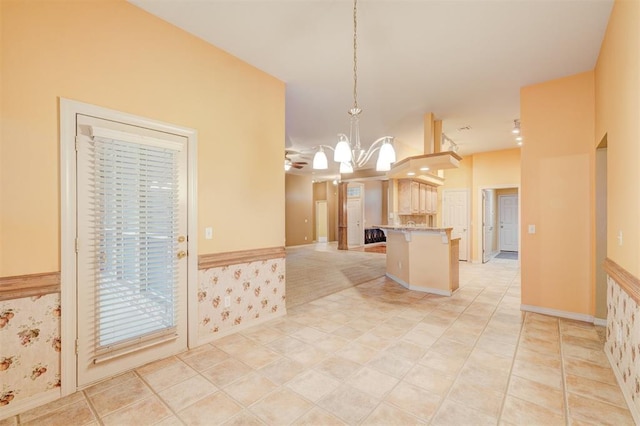 kitchen with a kitchen breakfast bar, light tile patterned floors, hanging light fixtures, and ceiling fan with notable chandelier