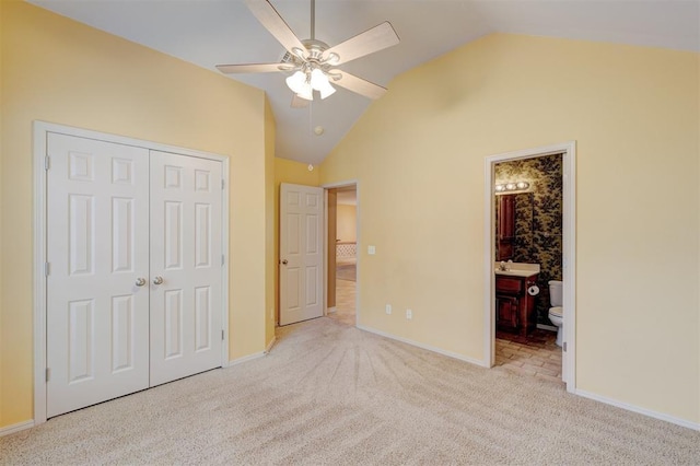 unfurnished bedroom with light carpet, ceiling fan, high vaulted ceiling, connected bathroom, and a closet