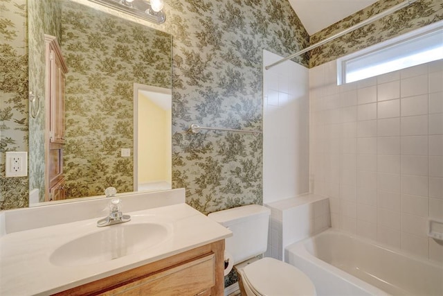 full bathroom featuring vanity, tiled shower / bath combo, and toilet