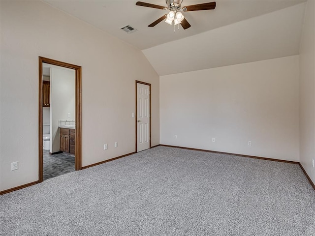 unfurnished bedroom featuring dark carpet, ensuite bathroom, vaulted ceiling, ceiling fan, and a closet