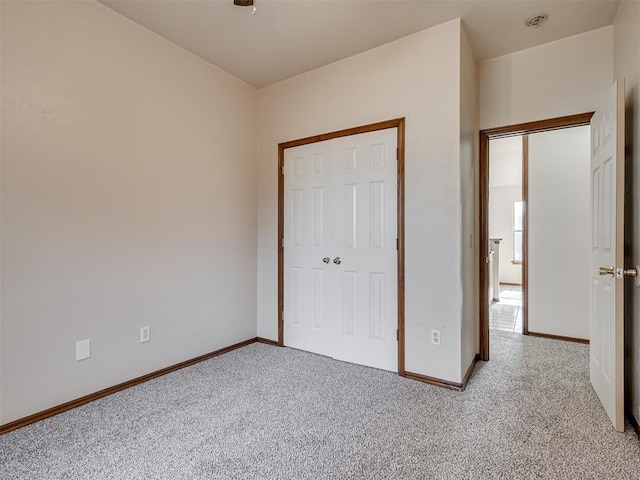 unfurnished bedroom featuring a closet and light colored carpet