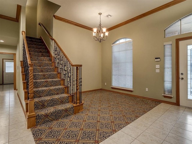 entrance foyer featuring a chandelier, ornamental molding, a healthy amount of sunlight, and light tile patterned flooring