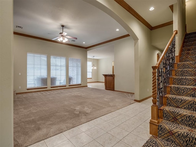 unfurnished living room featuring light tile patterned floors, ceiling fan with notable chandelier, and ornamental molding