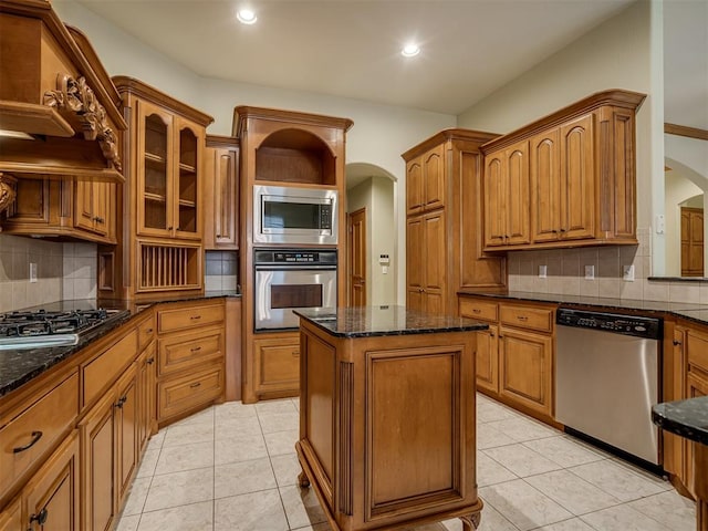 kitchen featuring appliances with stainless steel finishes, backsplash, a kitchen island, and dark stone countertops