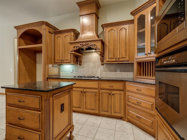 kitchen with custom exhaust hood, dark stone counters, light tile patterned floors, tasteful backsplash, and stainless steel appliances