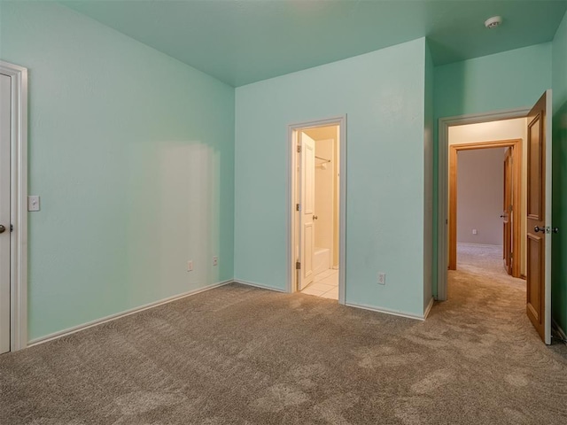 unfurnished bedroom with connected bathroom and light colored carpet