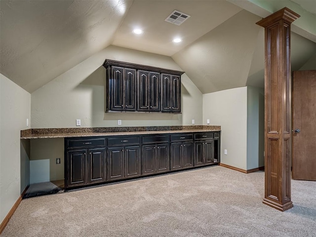 interior space featuring lofted ceiling, light carpet, and decorative columns