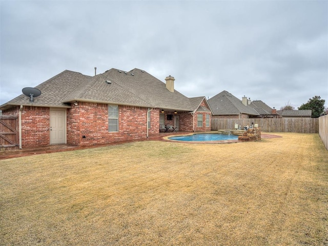 back of property featuring a yard and a fenced in pool