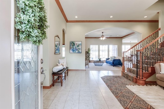 entryway featuring stairway, light tile patterned floors, baseboards, arched walkways, and ceiling fan