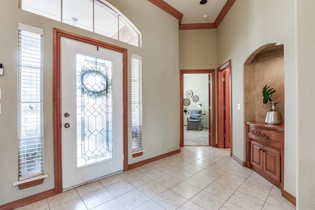 foyer with light tile patterned flooring, arched walkways, crown molding, and baseboards