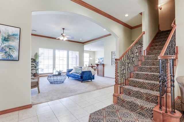 stairs featuring arched walkways, carpet, crown molding, and ceiling fan