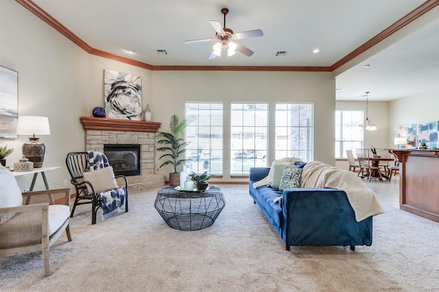 carpeted living area featuring ornamental molding, visible vents, ceiling fan with notable chandelier, and a stone fireplace