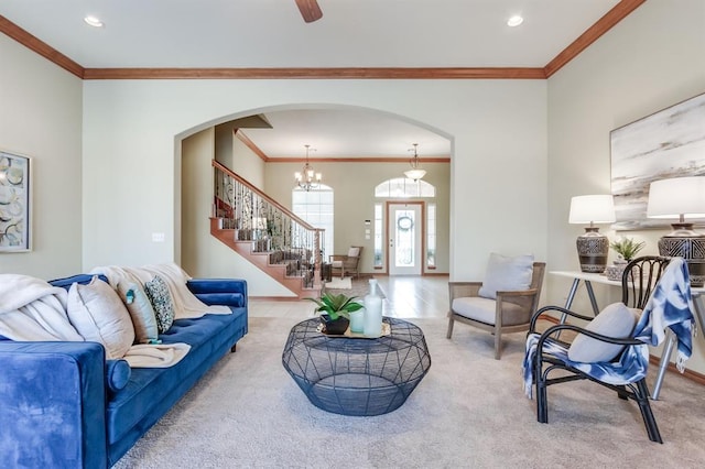 carpeted living area with arched walkways, stairs, baseboards, and crown molding